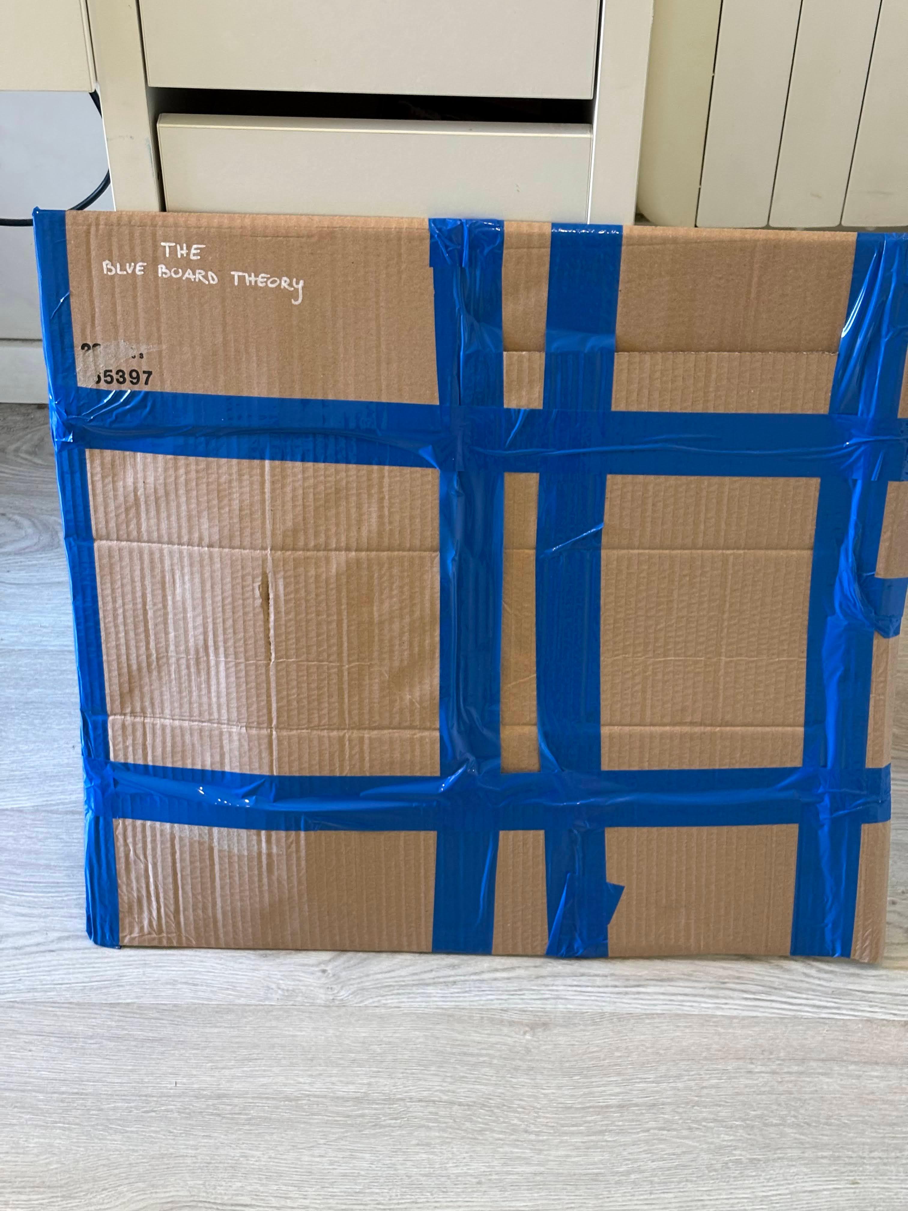 The Blue Board Theory packaged flat in a protective, taped box ready to ship.