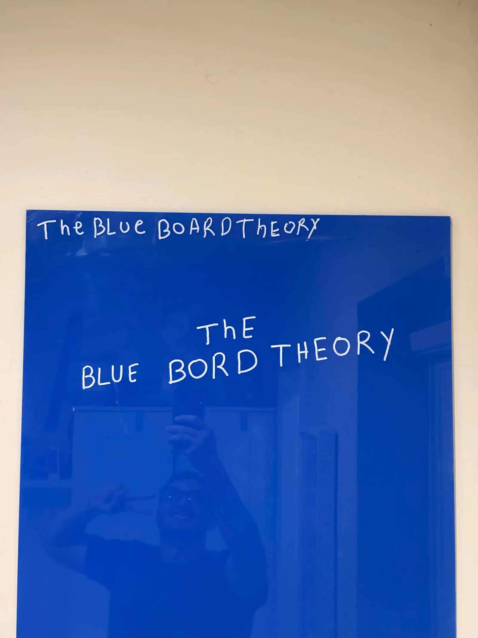 Close-up of the deep cobalt acrylic board with hand-lettered white marker writing.